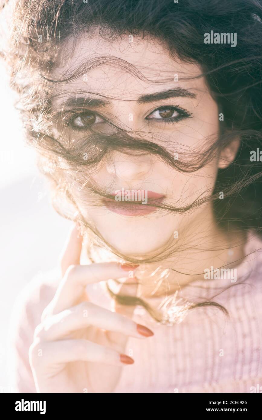 Schöne junge Frau Hand berühren Gesicht Blick auf Kamera Stockfoto