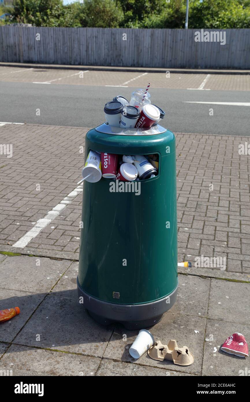 Eine gut überbenutzte Mülltonne auf einem Parkplatz neben der Durchgangsstraße, die bei Passanten beliebt ist. Stockfoto