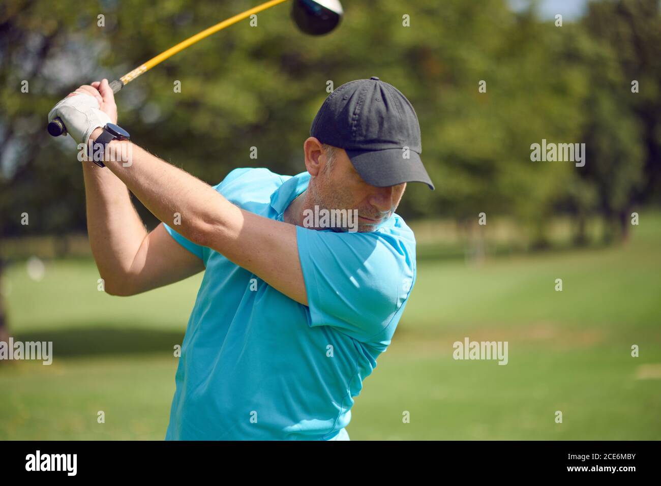 Männlicher Golfer schwingt am Ball mit einem Fahrer als Er macht seinen Schuss auf einem Golfplatz in einem Nahaufnahme Oberkörperansicht in einem gesunden aktiven Lebensstil concep Stockfoto