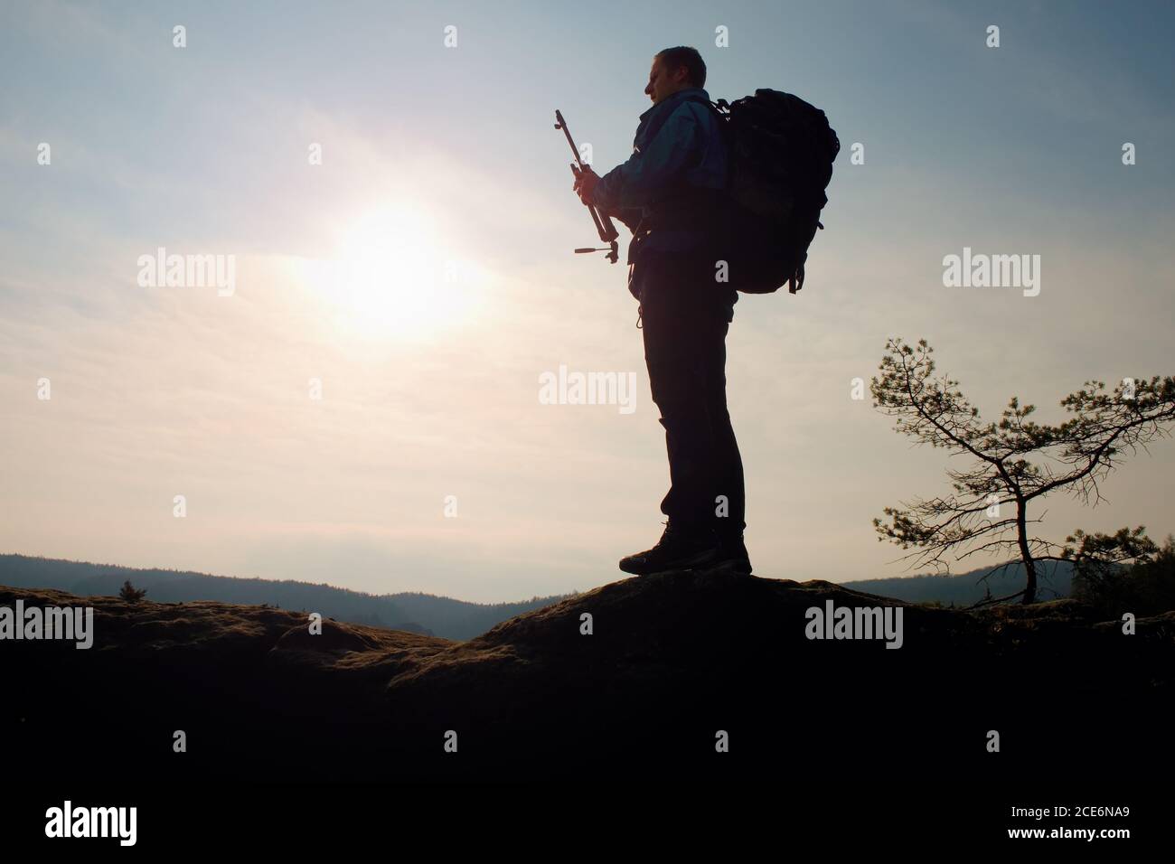 Allein erwachsener Mann Rucksacktourist bei Sonnenaufgang bei freiem Blick auf Berggipfel Stockfoto
