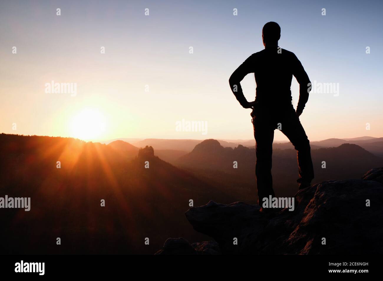 Ein Mann hat seine Hände auf Hüften. Sportler Silhouette in der Natur bei Tagesanbruch. Stockfoto