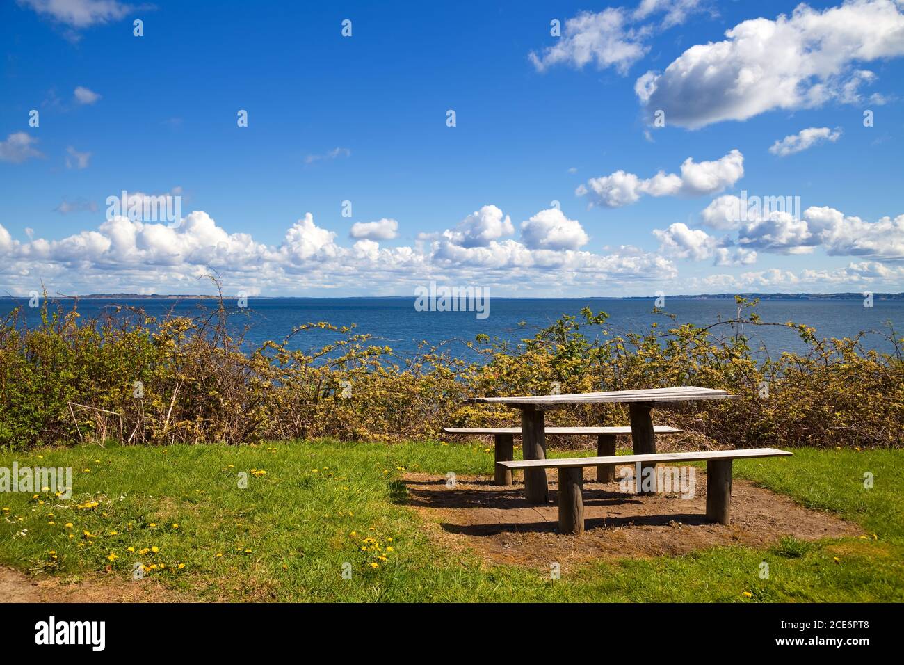 Schöne Küste mit Picknick-Tisch und Bänke auf einem sonnigen Sommertag Stockfoto
