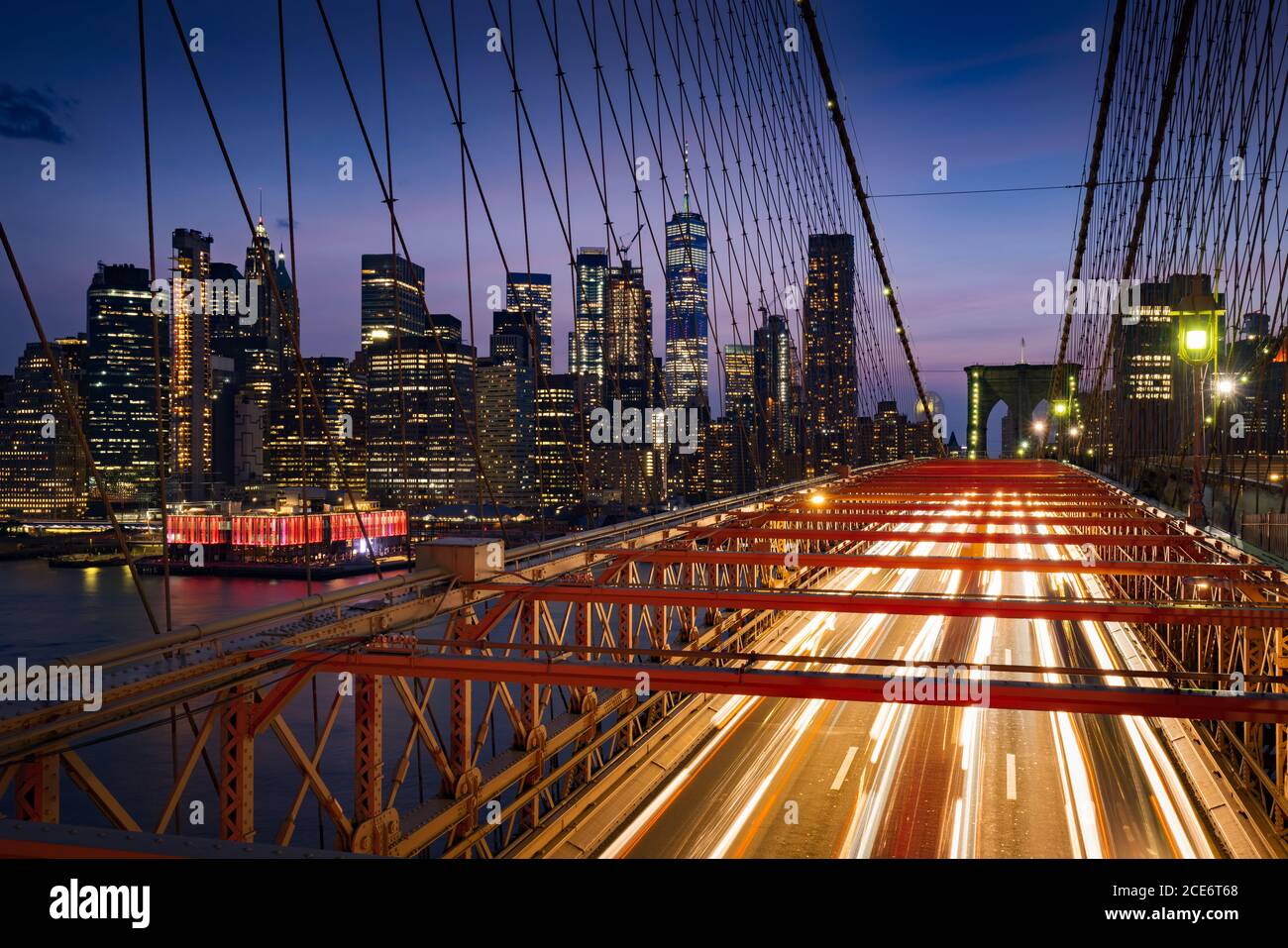 Wolkenkratzer in Lower Manhattan bei Dusk und Brooklyn Bridge mit leichten Pfaden. Abend in New York City, NY, USA Stockfoto