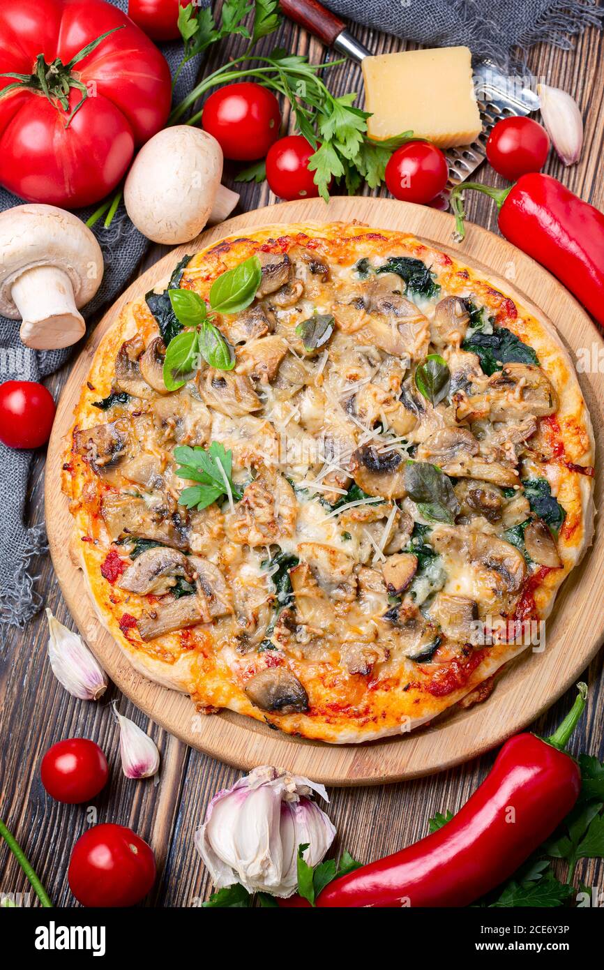 Pizza mit Tomaten, Pilzen, Käse und grünem Basilikum. Stockfoto