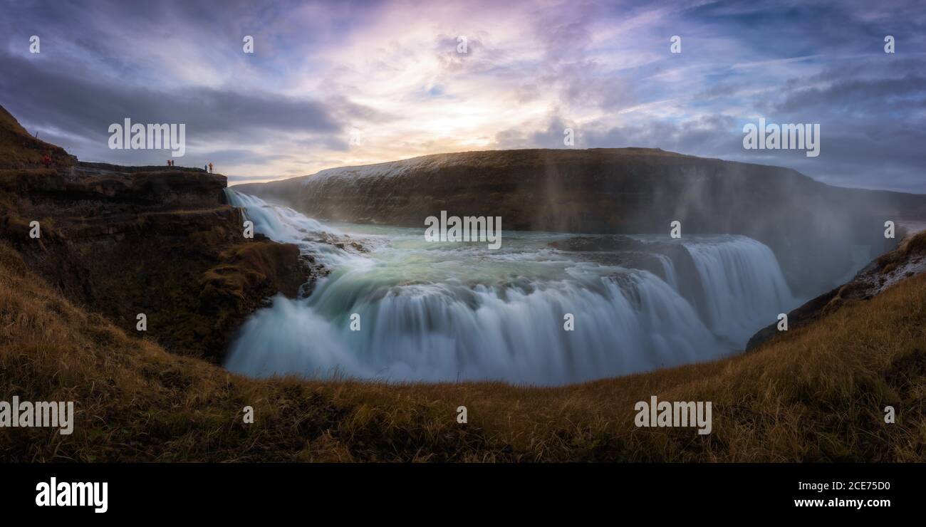 Atemberaubende Aussicht auf riesigen Wasserfall mit schnellen Strömung gegen bewölkt Himmel bei Sonnenuntergang Stockfoto