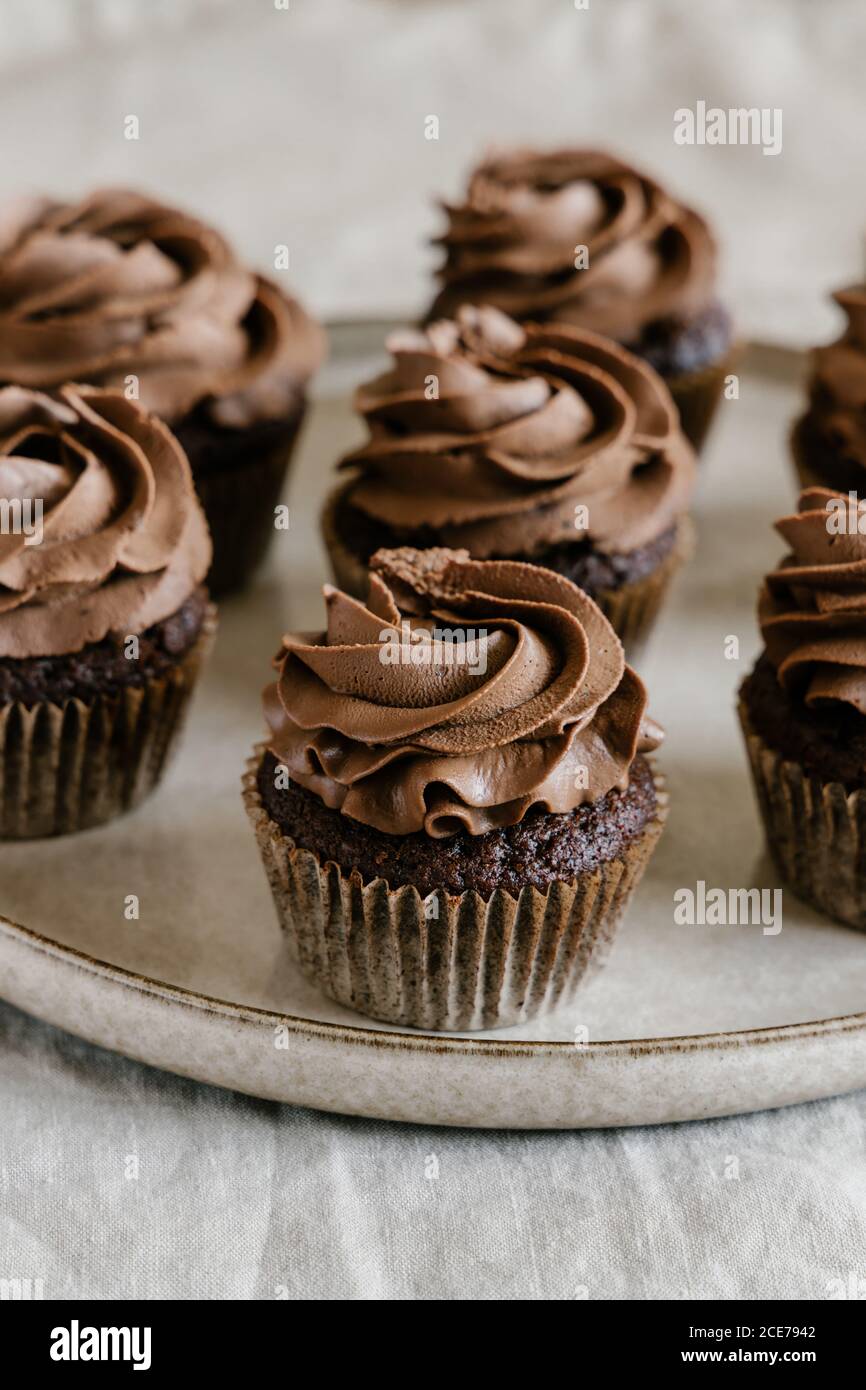 Appetitliche süße Schokoladen-Cupcakes mit Schokoladenbutter-Sahne serviert Rundes Tablett auf dem Tisch Stockfoto