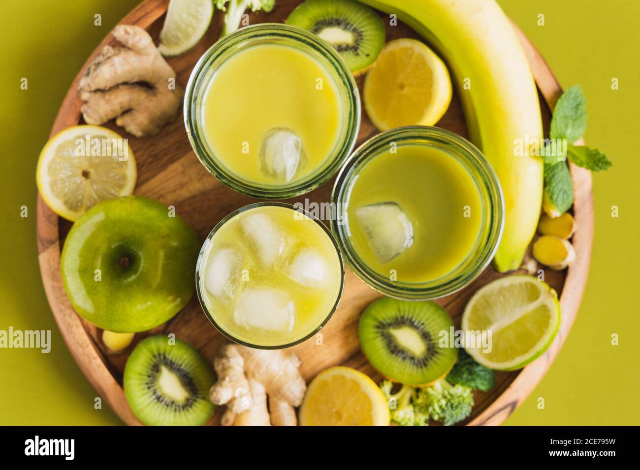 Von oben Gläser mit gesunden Detox Getränke mit Eis Würfel auf Holzplatte mit Apfel und Ingwer gelegt Stockfoto