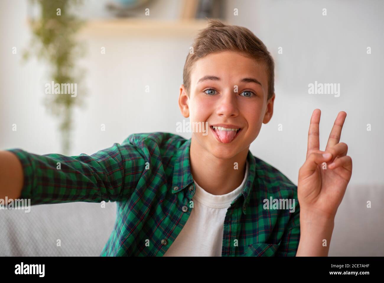 Niedlich teen junge nehmen Selfie, zeigt Zunge und Frieden Geste Stockfoto