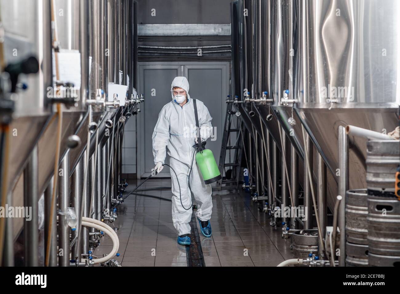 Brauer arbeitet mit Industrieanlagen in der Brauerei in Schutzanzug Und reinigt Stockfoto