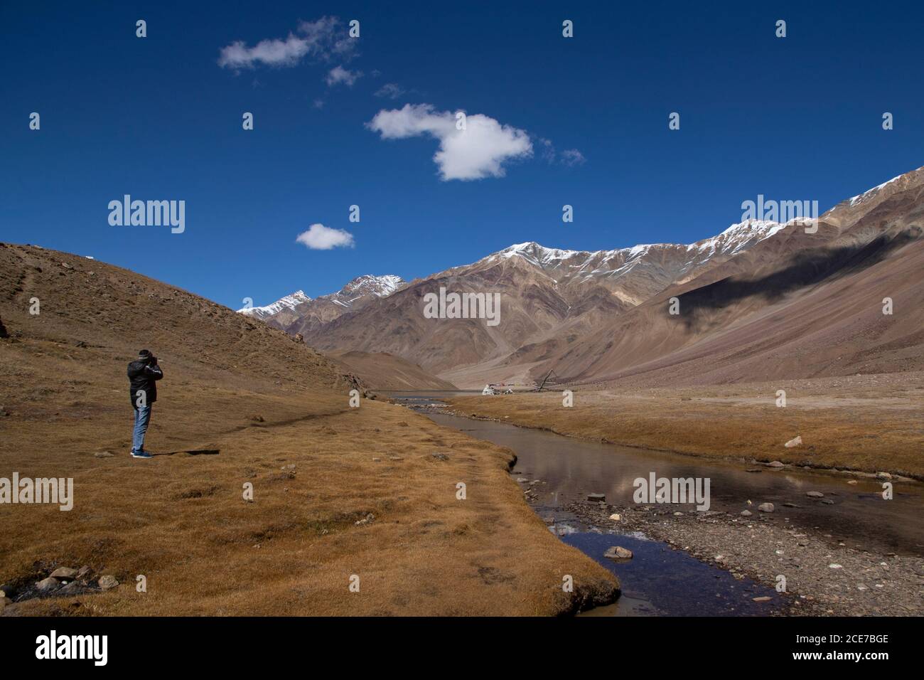 Ein Touristenfotograf in der Nähe von Chandratal verwendet seine Kamera, um Fotos von Landschaft klicken - blauer Himmel mit weißen Wolken, Schatten der Wolken, Reflexion. Stockfoto