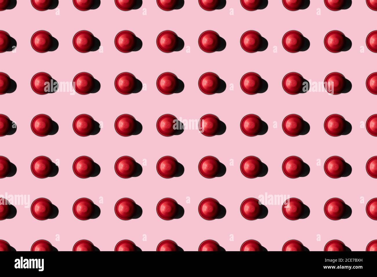 Draufsicht auf rote Kaffeepads in geraden Reihen Als Nahtloses Muster auf rosa Hintergrund Stockfoto