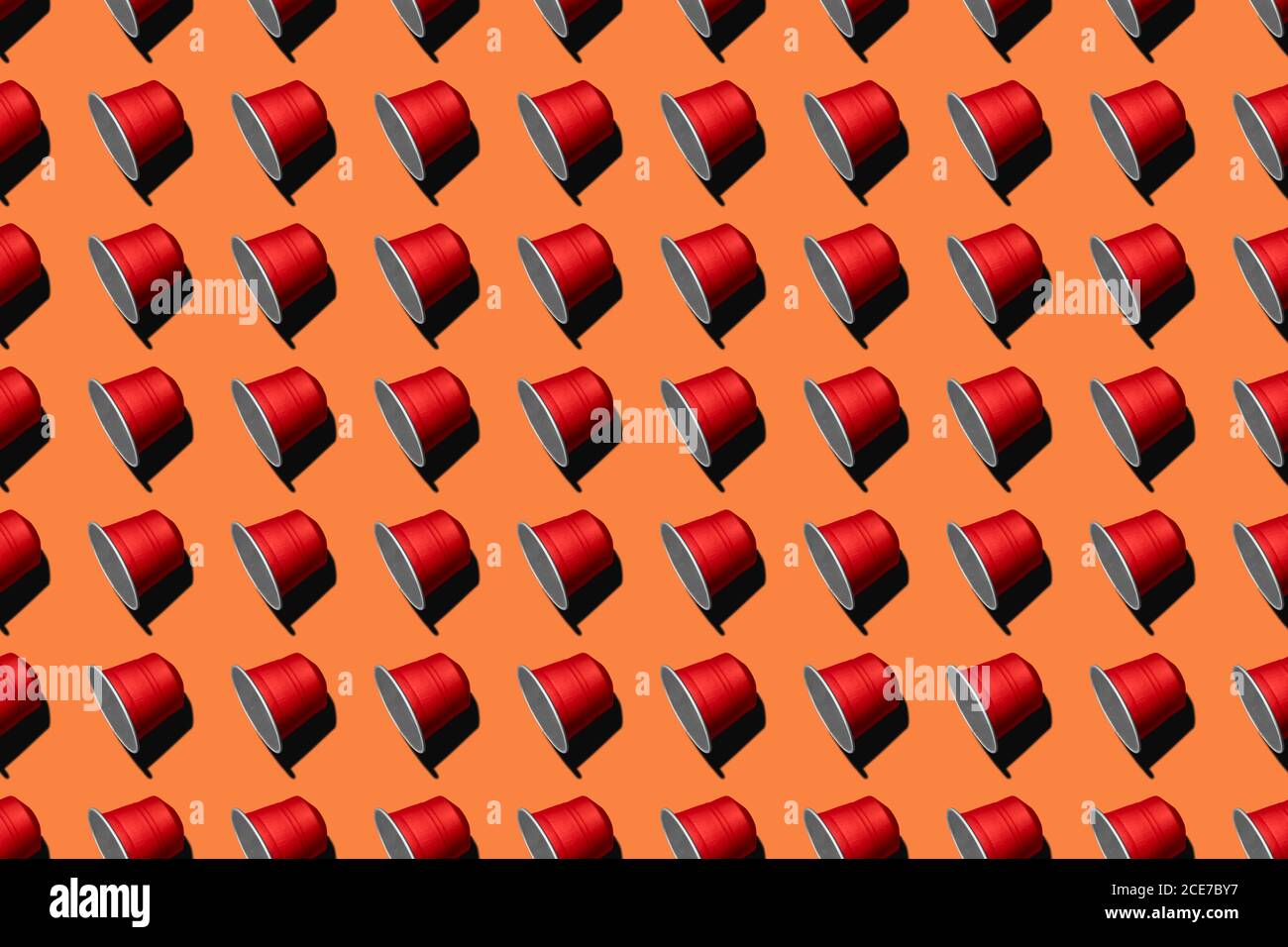 Draufsicht auf rote Kaffeepads in geraden Reihen Als nahtloses Muster auf orangefarbenem Hintergrund Stockfoto
