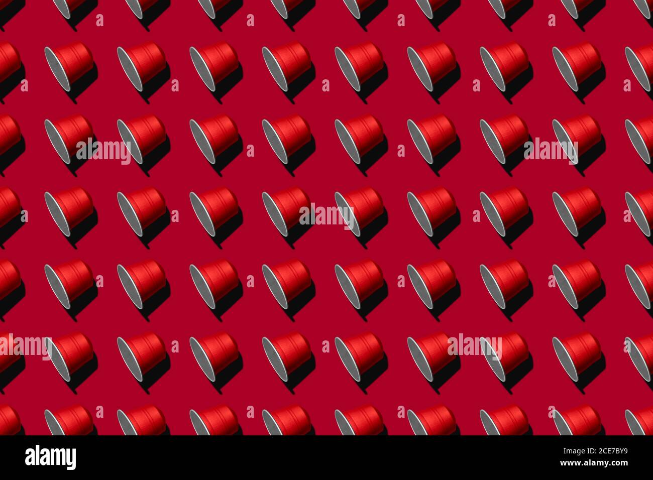 Draufsicht auf rote Kaffeepads in geraden Reihen Als nahtloses Muster auf rotem Hintergrund Stockfoto
