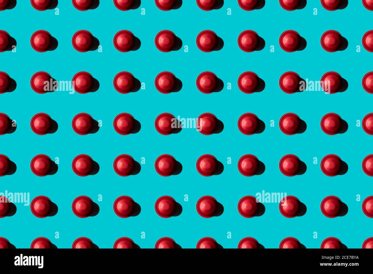 Draufsicht auf rote Kaffeepads in geraden Reihen Als nahtloses Muster auf blauem Hintergrund Stockfoto