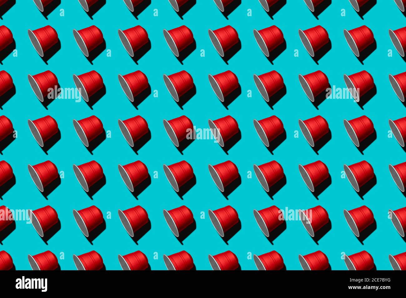 Draufsicht auf rote Kaffeepads in geraden Reihen Als nahtloses Muster auf blauem Hintergrund Stockfoto