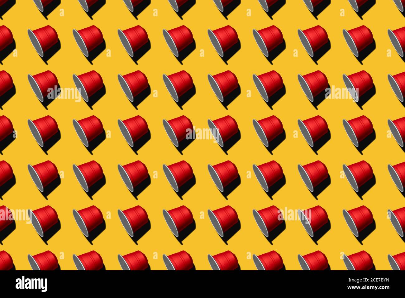 Draufsicht auf rote Kaffeepads in geraden Reihen Als nahtloses Muster auf gelbem Hintergrund Stockfoto