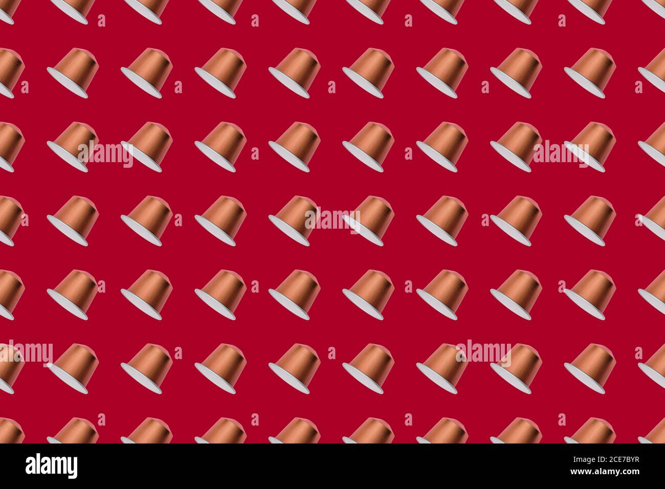 Draufsicht auf goldene Kaffeepads in geraden Reihen Als nahtloses Muster auf rotem Hintergrund Stockfoto