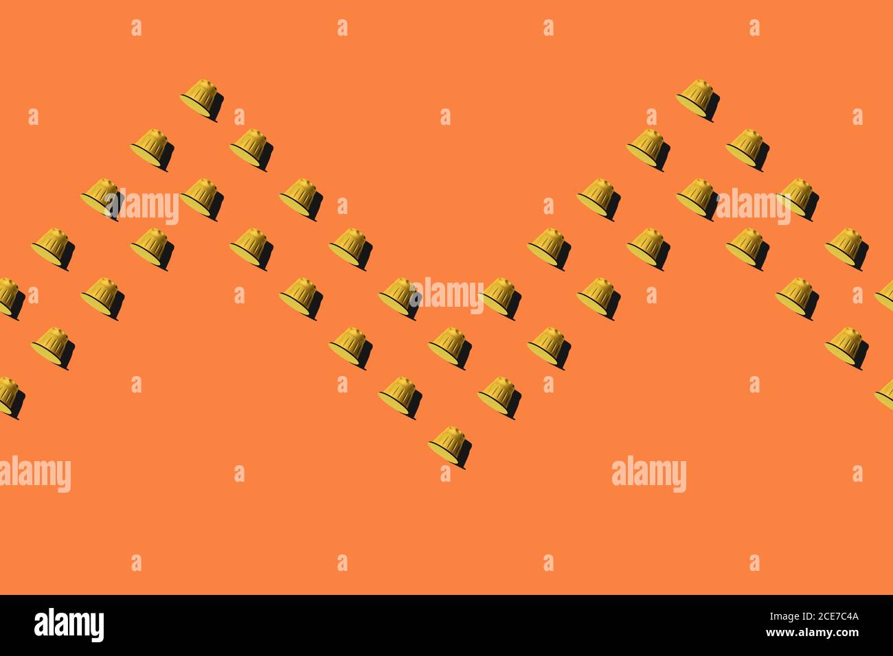 Ansicht der gelben Kaffeepads in geraden Reihen Als nahtloses Muster auf orangefarbenem Hintergrund Stockfoto