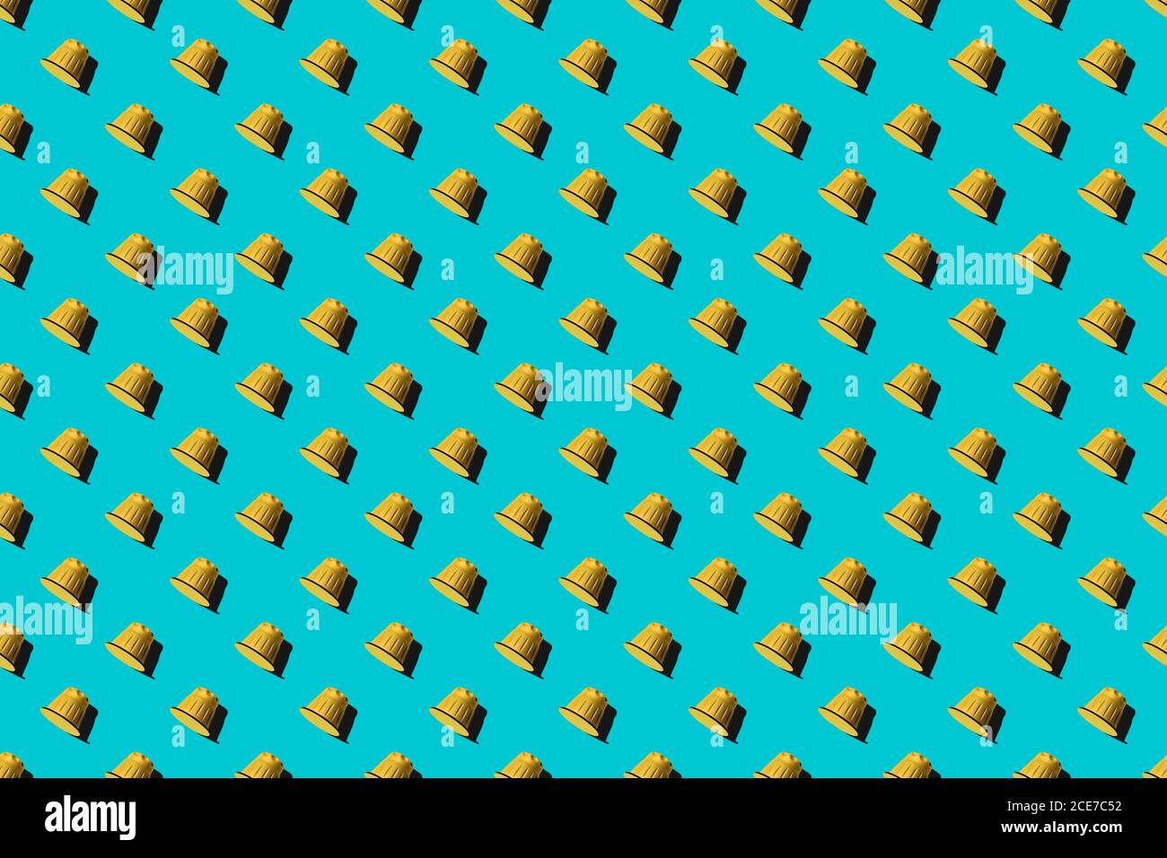 Ansicht der gelben Kaffeepads in geraden Reihen Als nahtloses Muster auf blauem Hintergrund Stockfoto