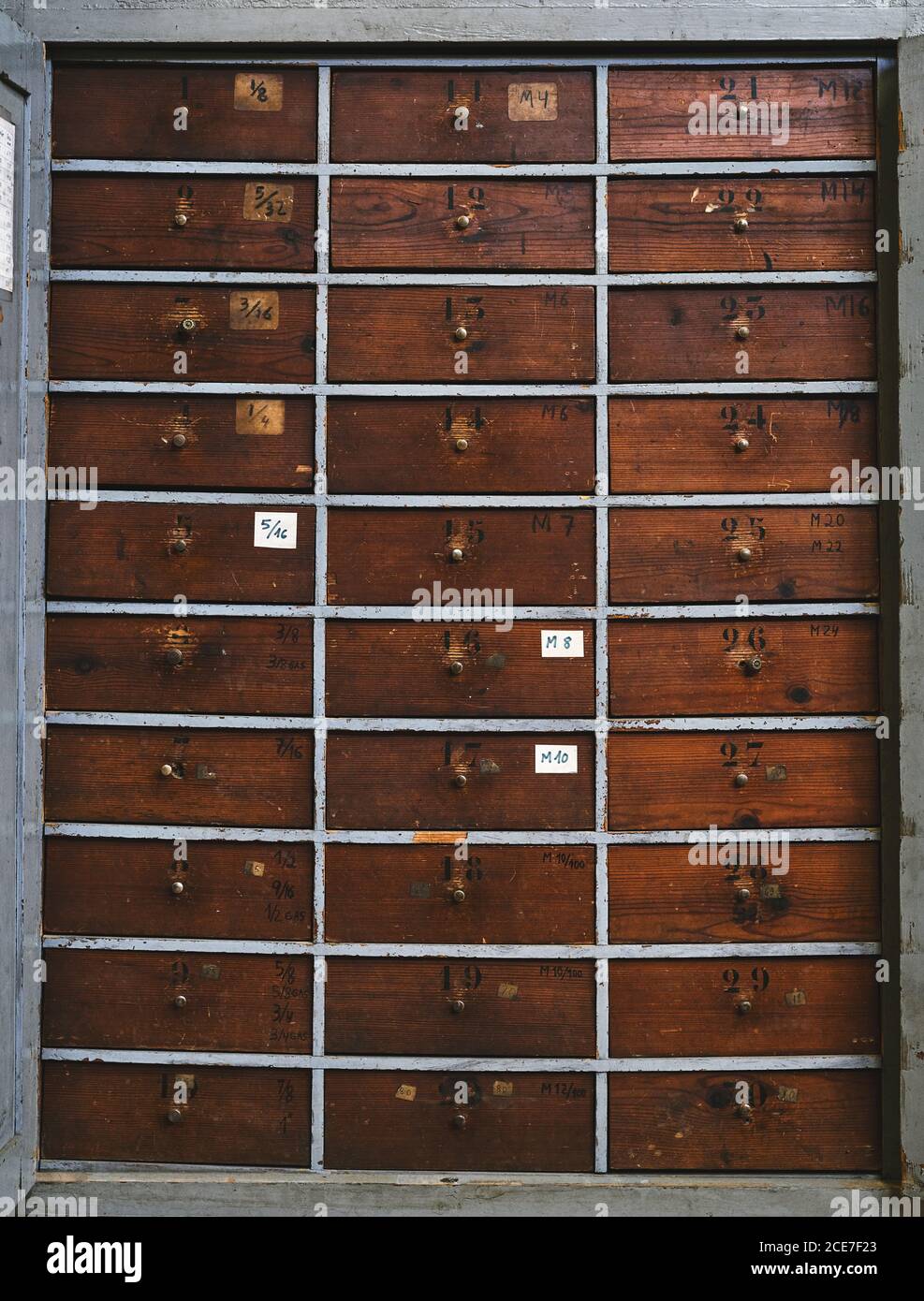 Archiv, das identische dunkelbraune Holzschubladen mit Zahlen darstellt Unebene Oberfläche mit Flecken in der Werkstatt Stockfoto