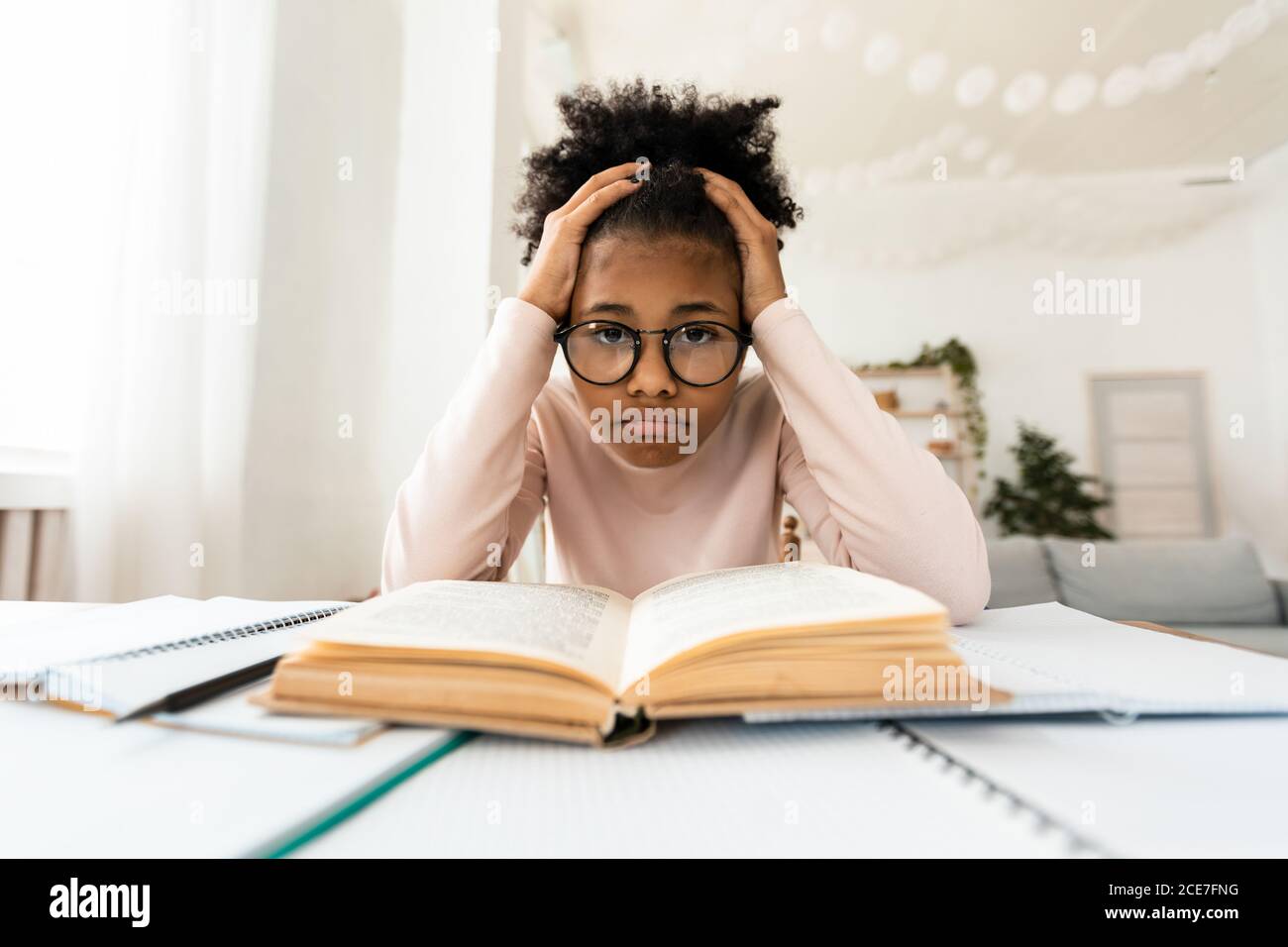 Frustriert Schwarz Mädchen Blick Auf Kamera Sitzen Bei Buch Im Innen Stockfoto