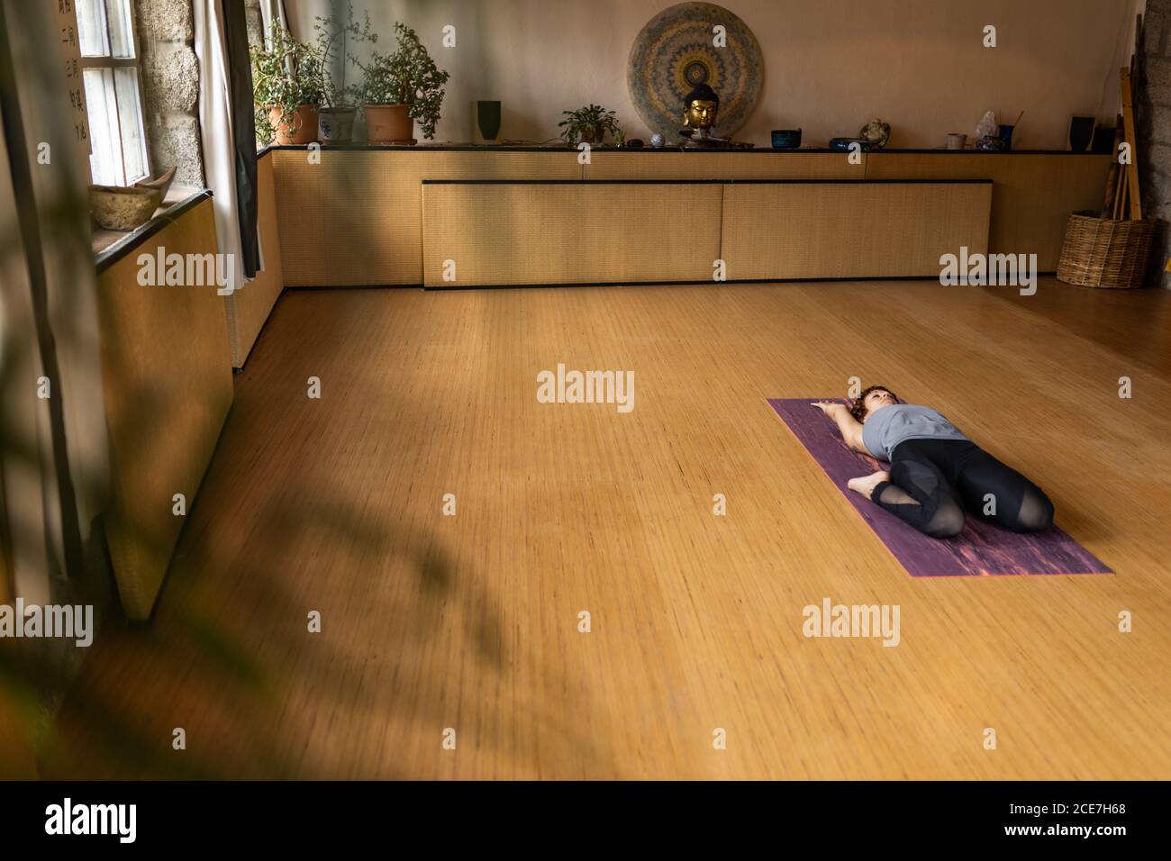 Von oben Ganzkörperansicht der flexiblen weiblichen Innenansicht Sportswear mit der erweiterten Rückenlage Hero Pose während der Shakti Yoga-Übung In geräumigem Studio mit Holzinterieur Stockfoto