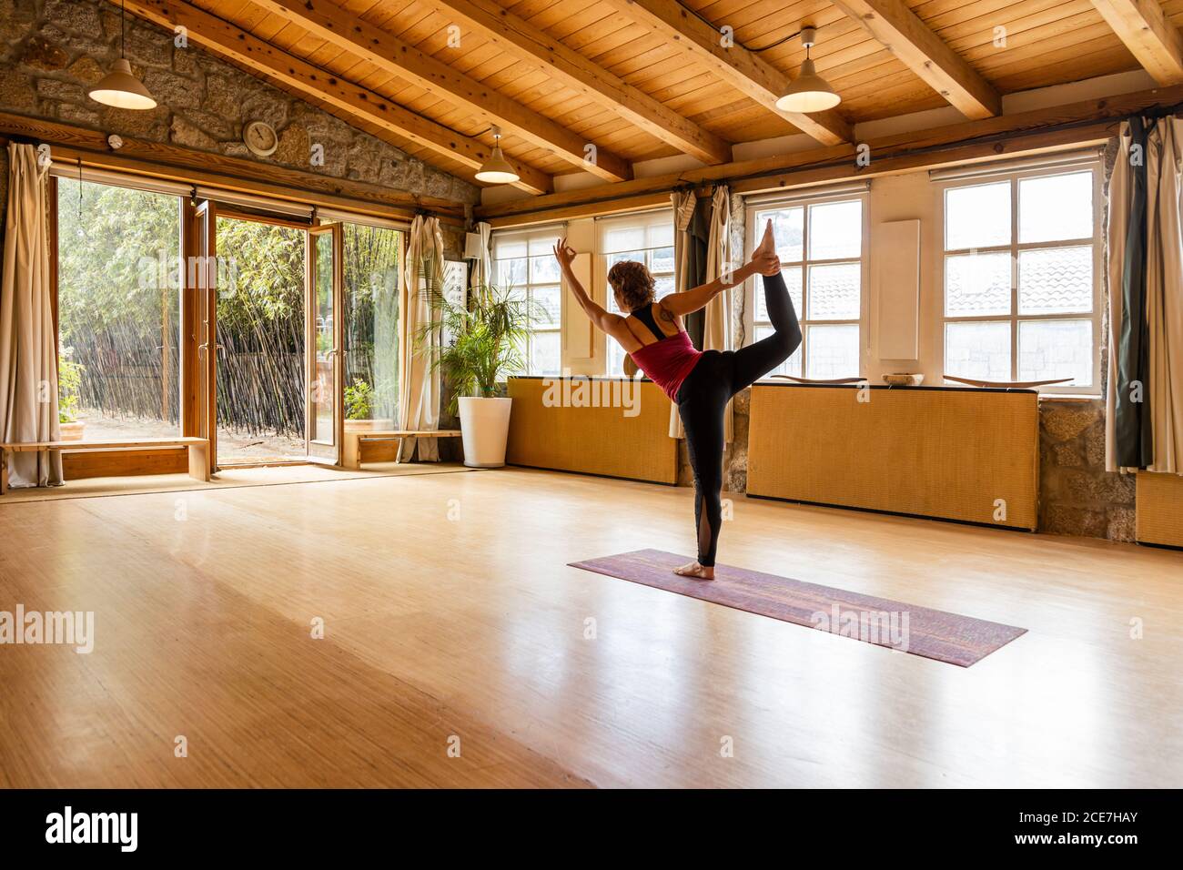 Ganzkörper-Seitenansicht der nicht erkennbaren weiblichen stehend in gedreht Lord of Dance Pose während Shakti Yoga Session in Spacious studio im tropischen Garten Stockfoto