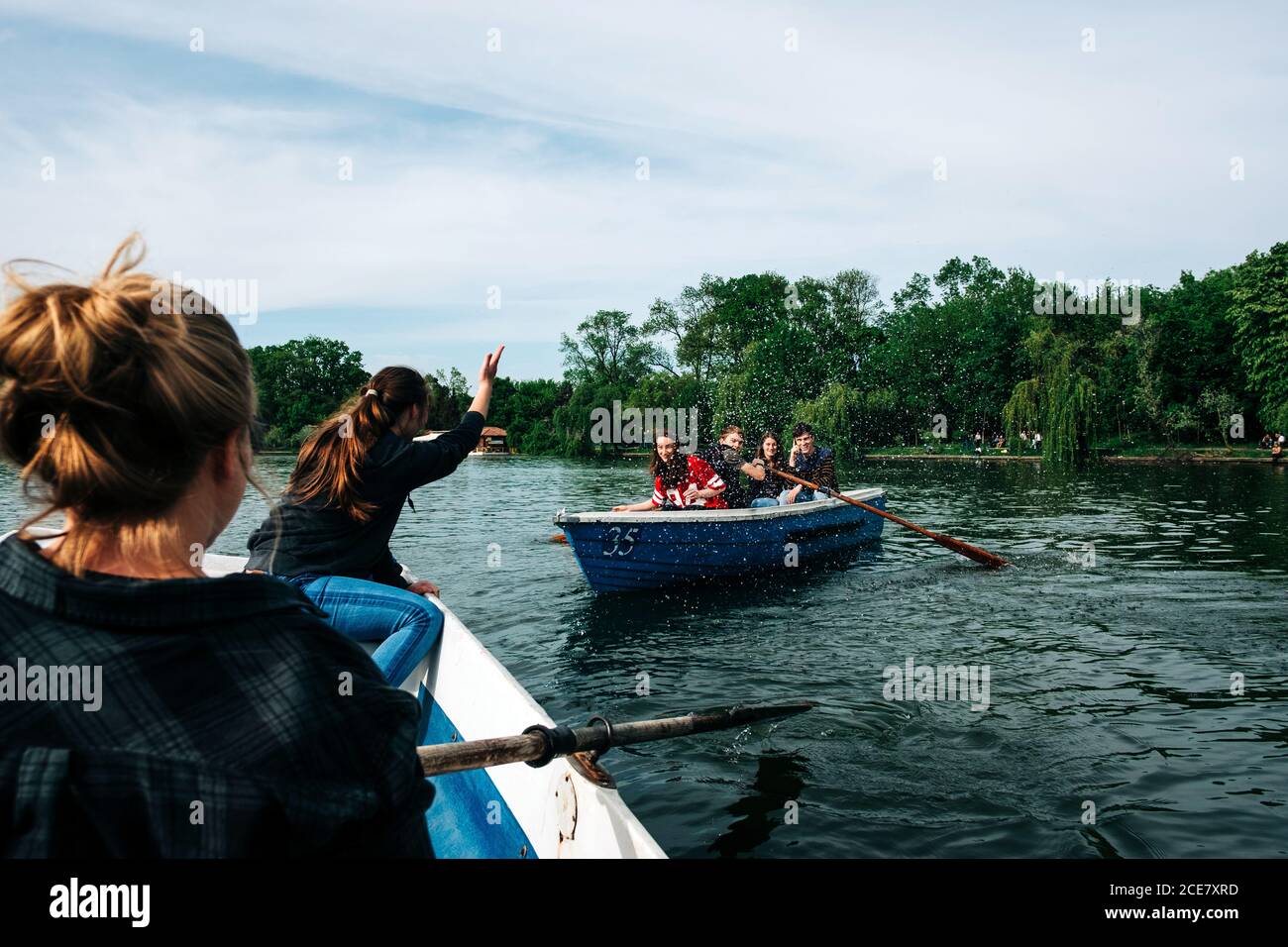 Gruppe junger Freunde, die auf Booten entlang des friedlichen Flusses schwimmen, während sie mit erhobenem Arm in St. George, Siebenbürgen, Rumänien, plaudern und gestikulieren Stockfoto