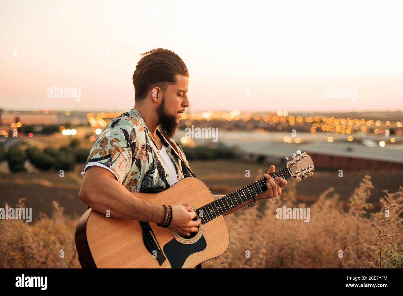Hipster Gitarrist in Casual Wear spielen klassische Gitarre im Stehen Im  Gras hinter dem Feld bei Sonnenuntergang unter ruhigem Himmel  Stockfotografie - Alamy
