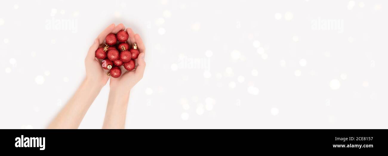 Frauen Hände halten rote Weihnachtskugeln auf einem grauen Hintergrund. Leuchtendes festliches Banner mit Platz für Kopien. Stockfoto