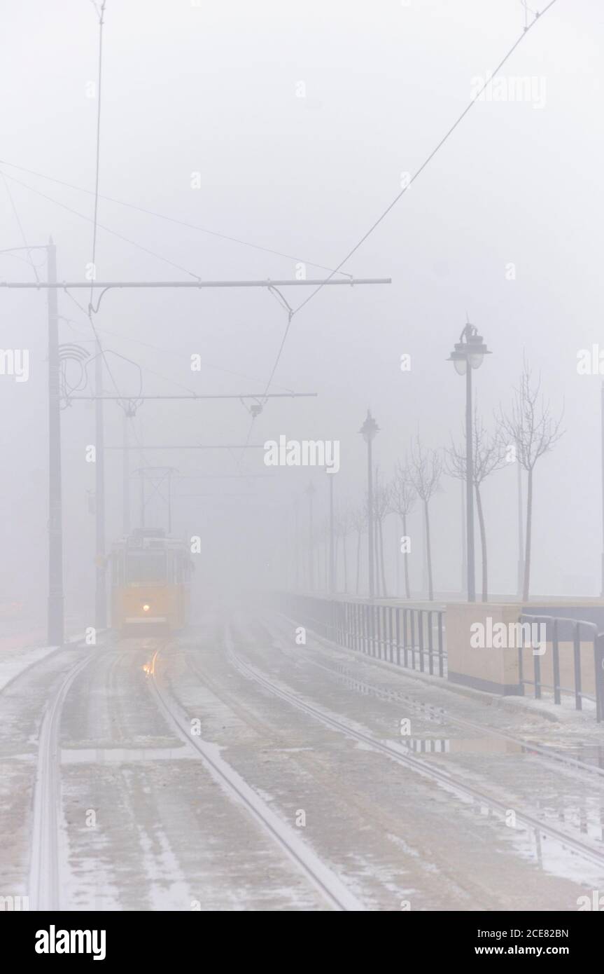 Die schäbige Metallbahn fährt langsam entlang der alten Eisenbahn während der Nebel Tag in der Stadt Stockfoto