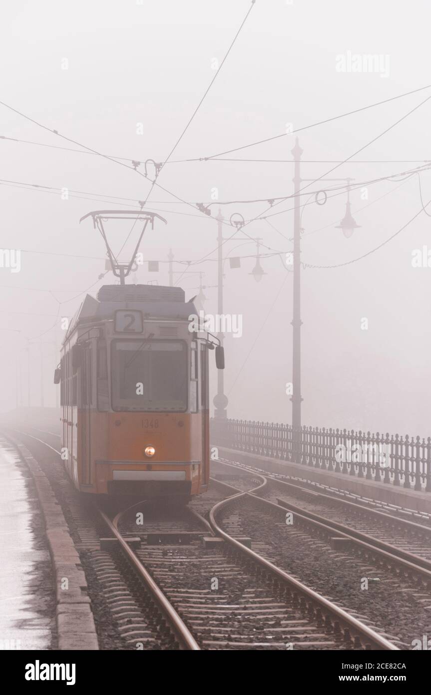 Die schäbige Metallbahn fährt langsam entlang der alten Eisenbahn während der Nebel Tag in der Stadt Stockfoto