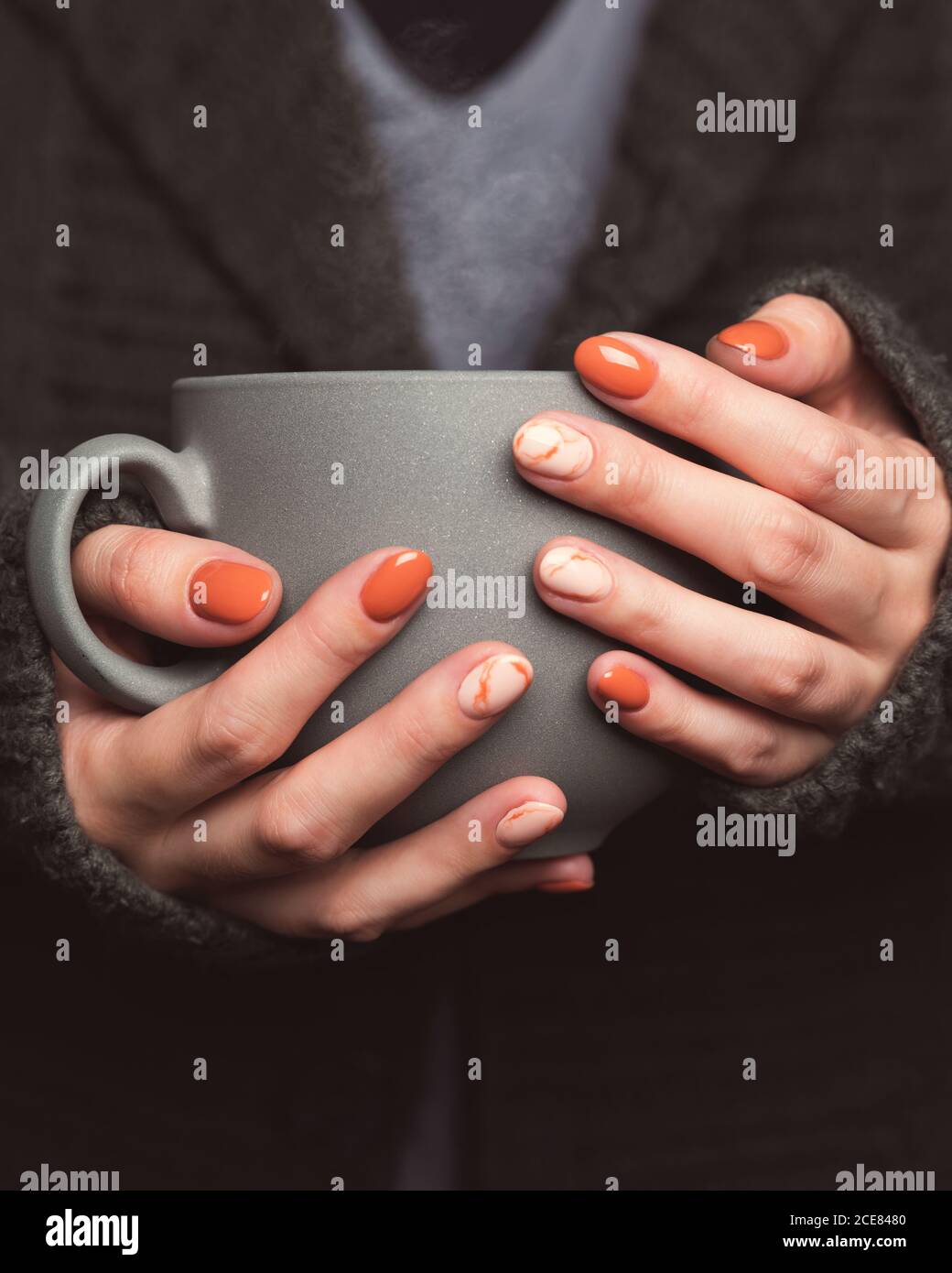 Frau hält eine Tasse heißen Tee. Grauer Strickpullover Stockfoto