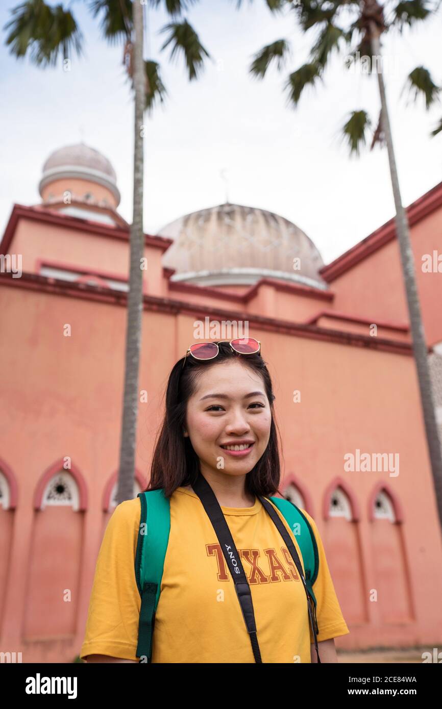 Asiatische weibliche Reisende in Bogenfenster der Pink Mosque stehen Während Sightseeing in Kota Kinabalu während der Sommerferien und suchen Bei der Kamera Stockfoto
