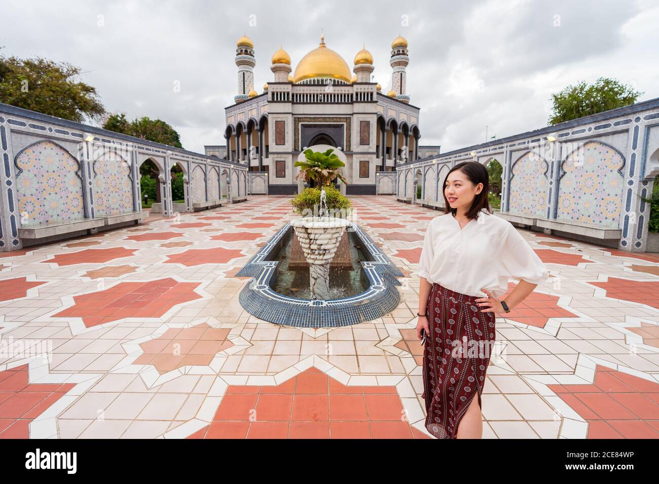 Lächelnde ethnische Reisende auf dem Platz in der Nähe von Jame ASR Hassanil Bolkiah Moschee während Sommerferien in Brunei und suchen Weg Stockfoto