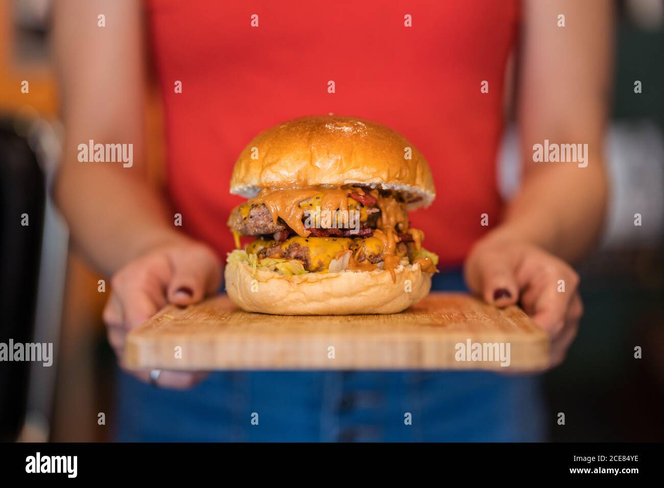 Ethnische Kellnerin Catering-Kunden in Café mit Burger auf Holz Schneidebrett Stockfoto