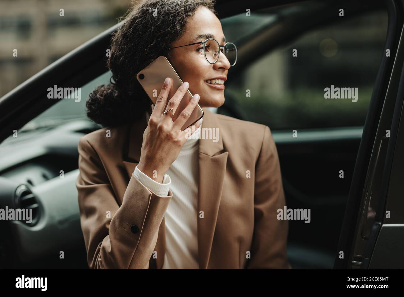 Geschäftsfrau sitzt in ihrem Auto und spricht am Telefon. Frau in Geschäftskleidung, die einen Anruf macht, während sie in ihrem Auto sitzt. Stockfoto