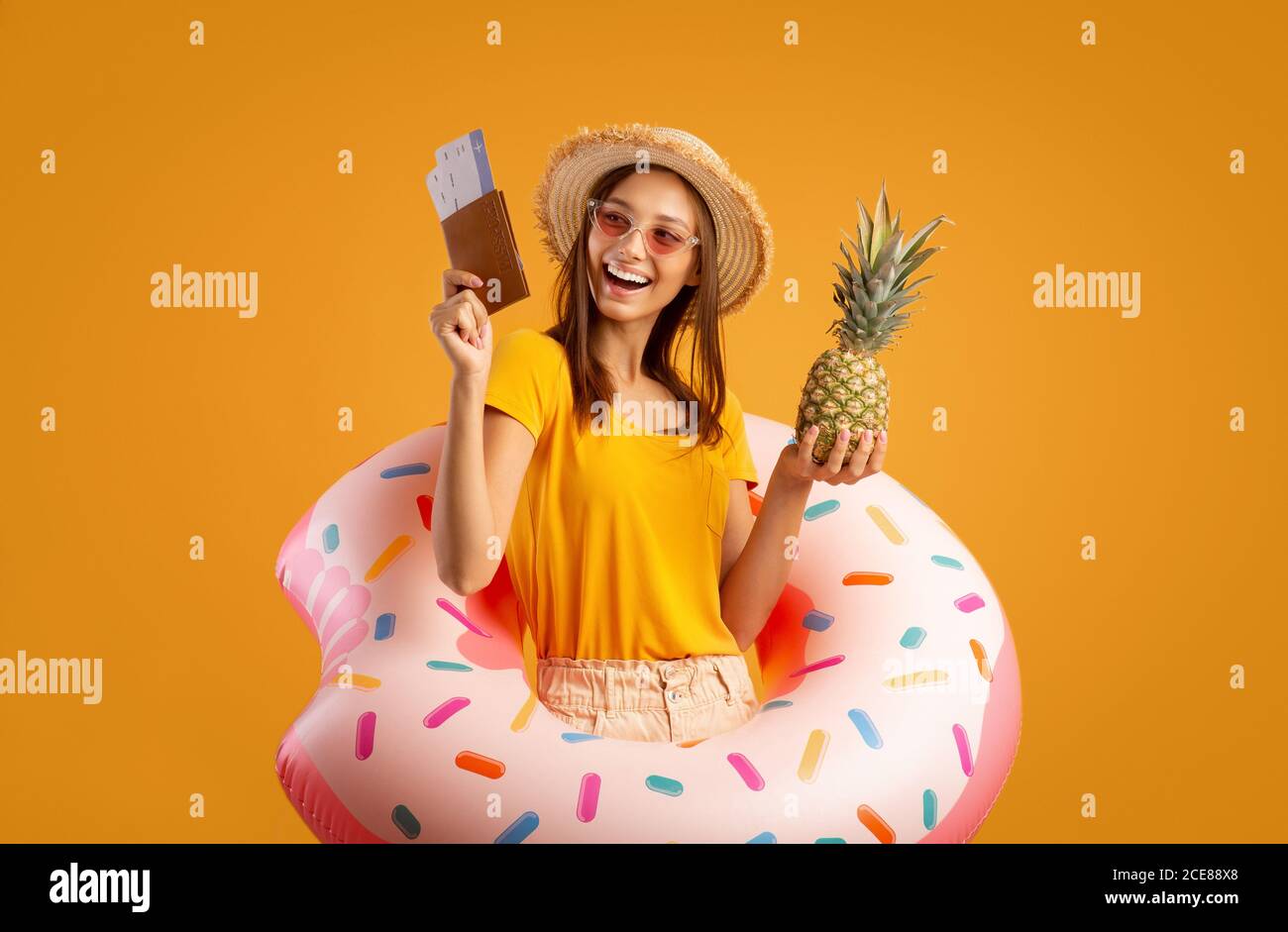 Fröhliches Mädchen mit Ananas und Pass trägt Gummiring Stockfoto