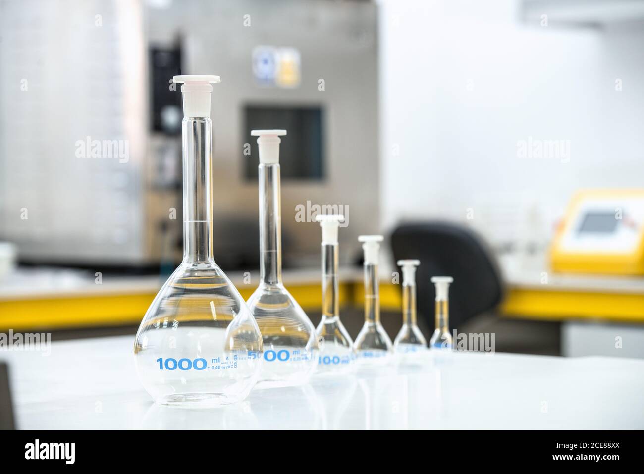 Verschiedene Glaskolben in Reihe auf dem Tisch platziert und vorbereitet Für Experimente im modernen Labor Stockfoto