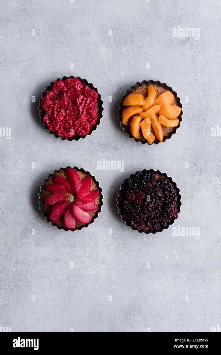 Draufsicht auf schmackhafte Kuchen mit verschiedenen reifen Früchten und Beeren auf dem Tisch arrangieren Stockfoto