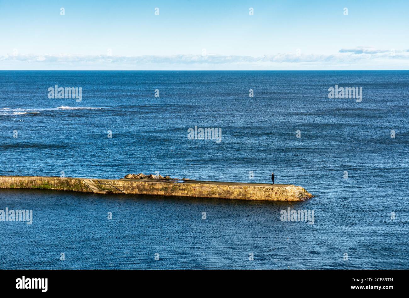 Tynemouth, England, Großbritannien - Februar 4, 2019: Ein Mann schaut auf das Meer von der Mole Cullercoats Hafen an der Nordsee der Tyneside. Stockfoto