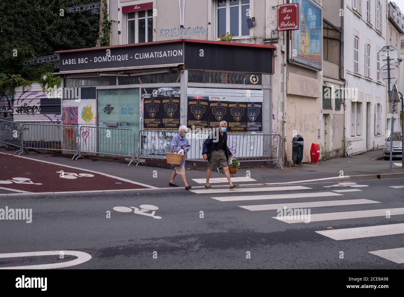 Angers, Frankreich - August 29 2020: Menschen mit Gesichtsschutzmaske beim Überqueren der Straße nach dem Einkaufen auf dem Marktplatz in Frankreich um Coronavirus zu verhindern, Konzept der Masken im Freien ist obligatorisch, respektieren Barriere Gesten Stockfoto
