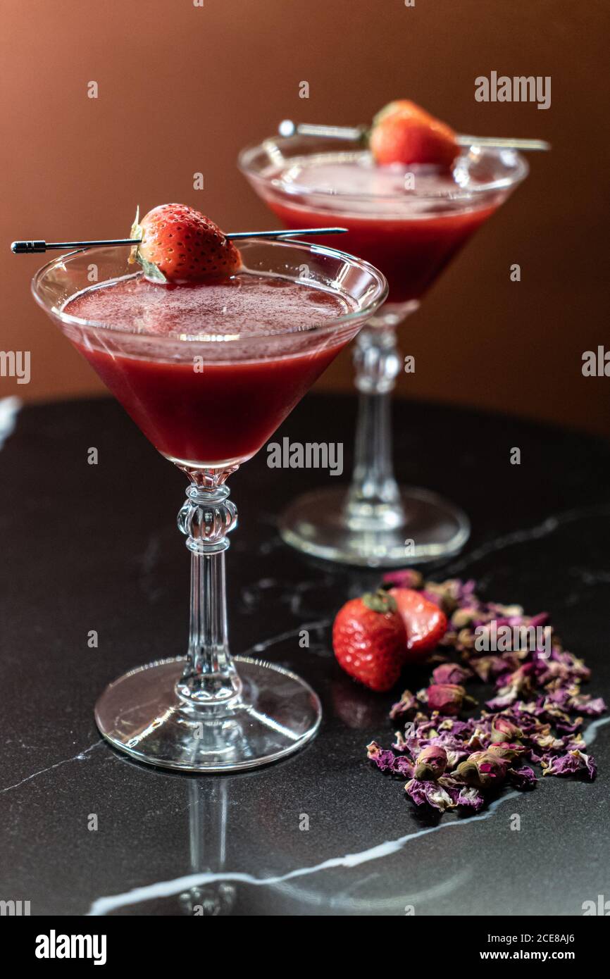 Gläser von süßem Alkohol trinken mit Erdbeere in der Nähe getrocknet platziert Blumenblätter auf dem Tisch im Restaurant Stockfoto