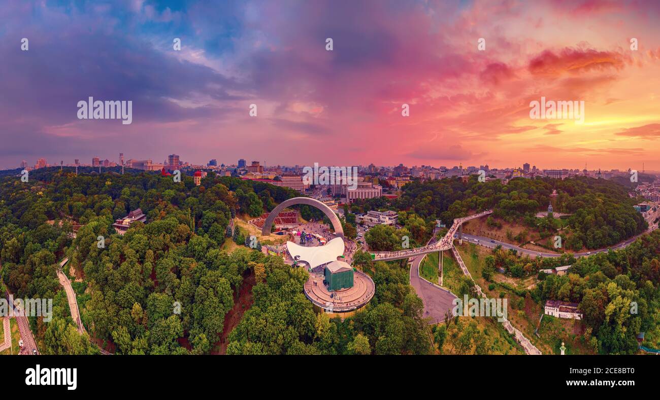 Panoramablick auf Kiew vom Himmel. Sonnenuntergang über Sommer Kiew mit Bogen der Freundschaft der Völker. Gefilmt auf Drohne. Luftaufnahme Stockfoto