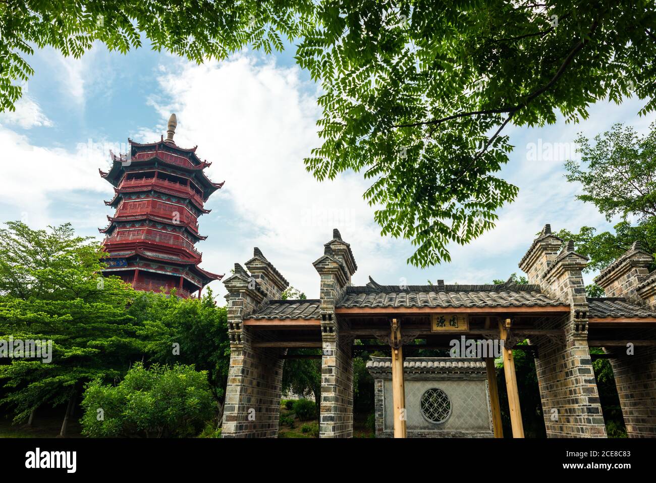 Niedriger Winkel malerischen Blick auf schöne dekorative Gebäude der traditionellen Chinesische Pagode von grünen Ästen gegen bewölktes Blau eingerahmt Himmel im Sommertag in Xiamen in China Stockfoto