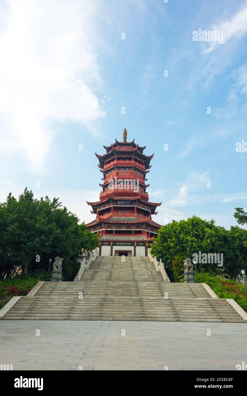 Niedriger Winkel malerische Aussicht auf schöne Treppe des dekorativen Gebäudes Der traditionellen chinesischen Pagode von grünen Ästen gegen eingerahmt wolkiger blauer Himmel am Sommertag in Xiamen in China Stockfoto