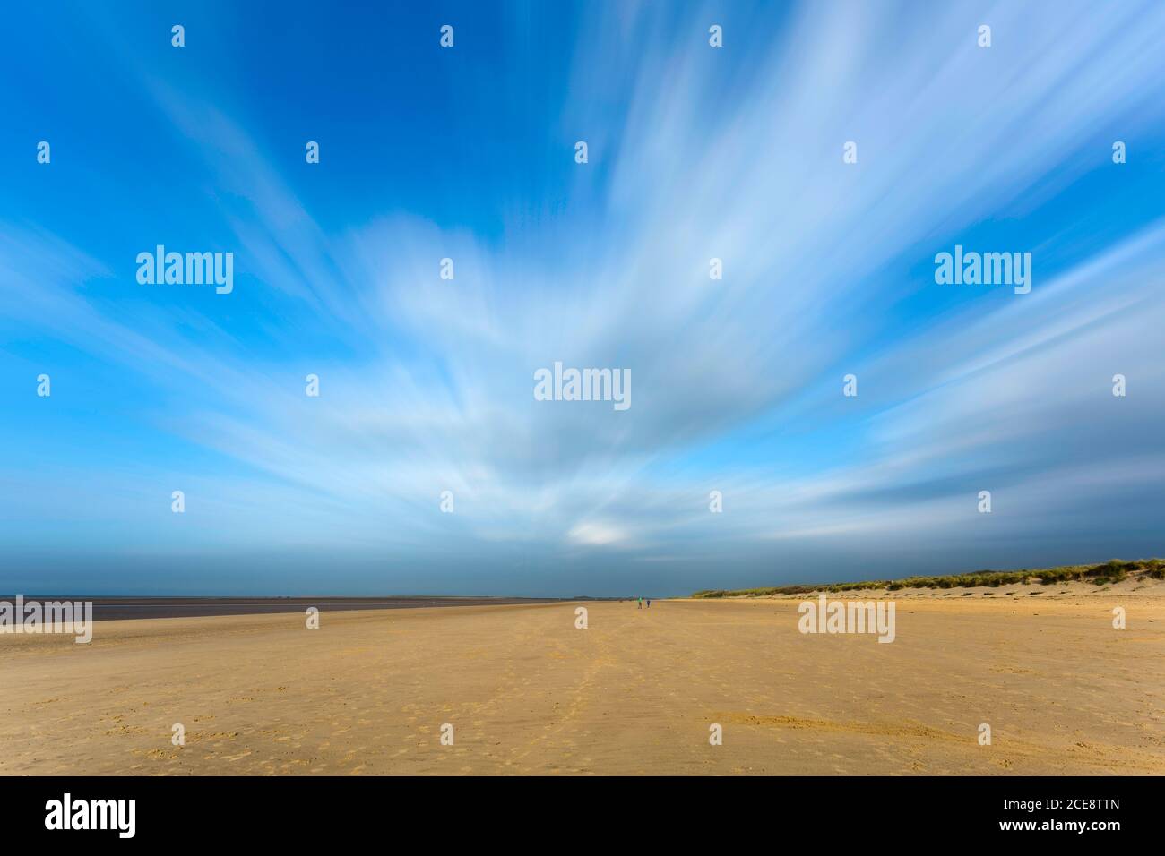 Wolken strömen über einen fast menschenleeren Strand. Stockfoto