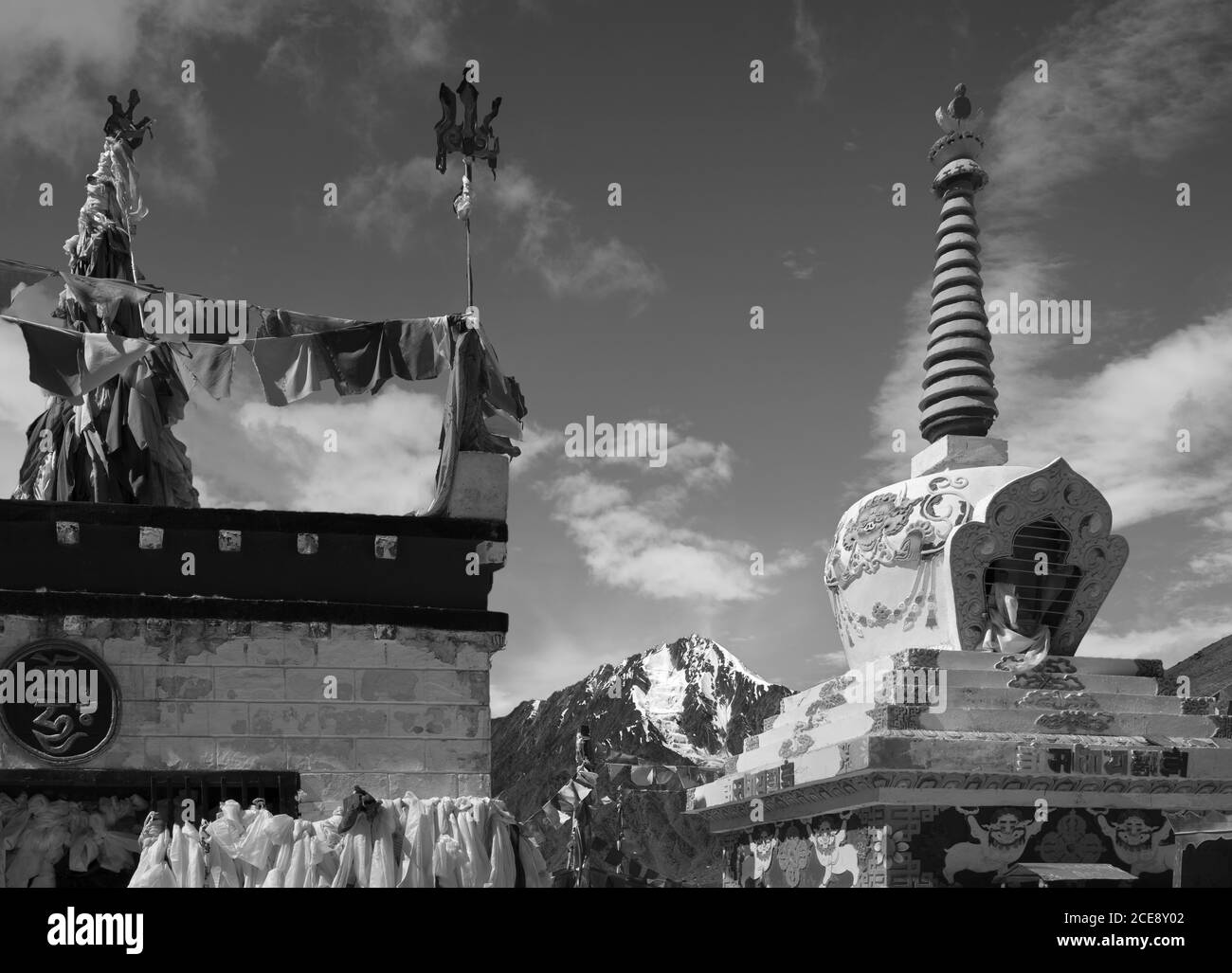 Buddhistische Stupa mit Gebetsfahnen, die den schneebedeckten Himalaya unter blauem Himmel zwischen Manali und Kaza, Himachal Pradesh, Indien, überragen. Stockfoto