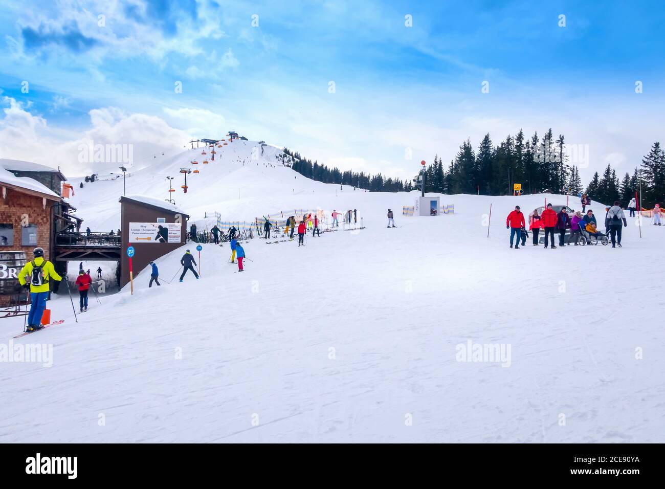 Saalbach, Österreich - 2. März 2020: Skifahrer und Snowboarder auf der Skipiste, Holzrestaurant dahinter Stockfoto