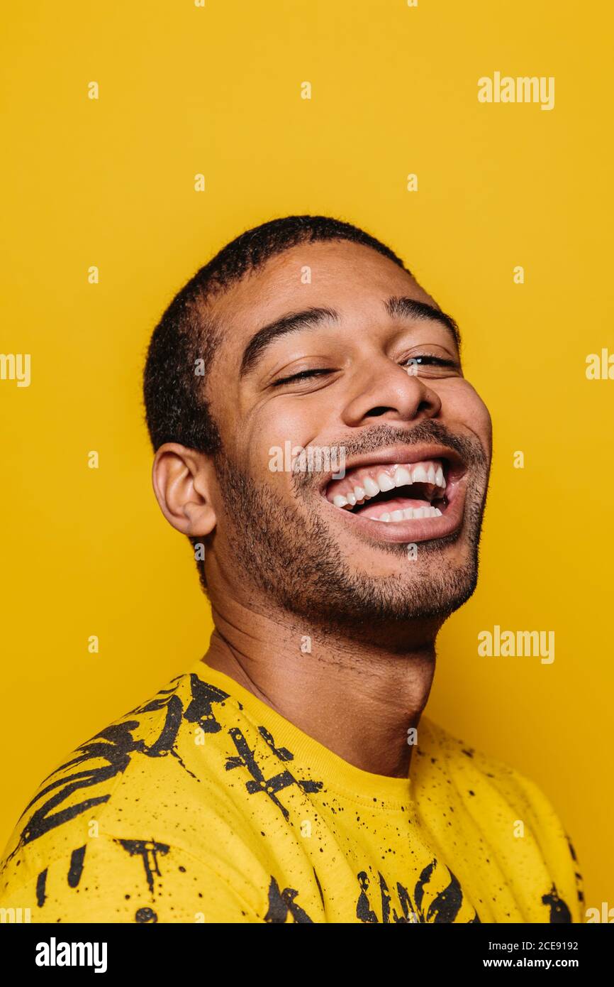 Porträt eines fröhlichen Mannes lächelnd und Blick auf die Kamera über Einfarbiger gelber Hintergrund Stockfoto
